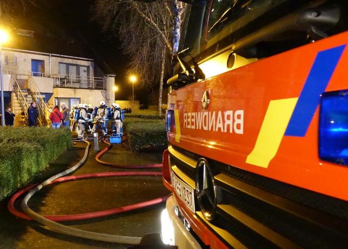 foto brandweerwagen en op achtergrond brandweermannen in actie