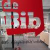 Op deze afbeelding van de Leo Pleysierbibliotheek zie je door het glas de boeken van de bib. Je ziet ook het logo van het bib op het glas.